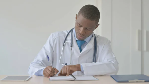 African-American Doctor Writing Medical Report in Clinic
