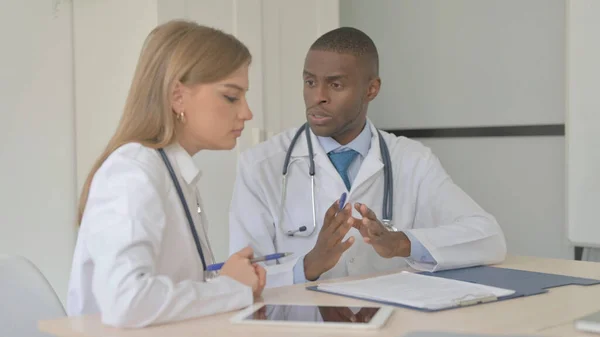 African-American Doctor and Female Doctor Discussing Medical Report, Paperwork