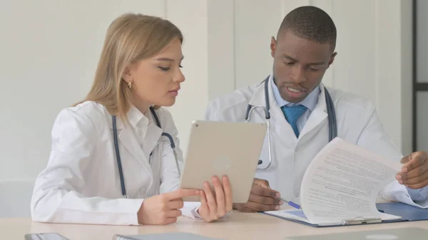 Female Doctor and African-American Doctor Working in Clinic, Using Tablet