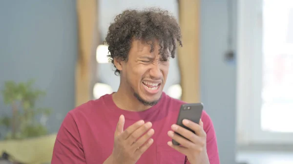 Shocked Young African Man Reacting to Loss on Smartphone