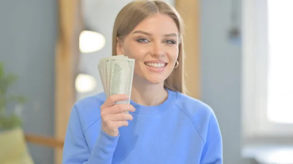 Young Woman Offering Dollar Bills in Creative Office