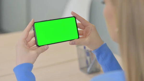 Young Woman Holding Horizontal Smartphone with Green Screen
