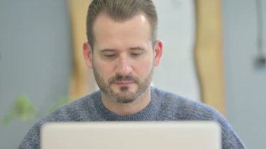 Close Up of Mature Adult Man Looking at Camera while using Laptop