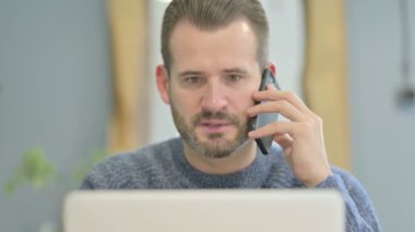 Close Up of Mature Adult Man Talking on Phone while using Laptop