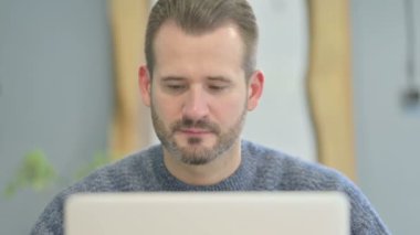 Close Up of Mature Adult Man Smiling at Camera while using Laptop