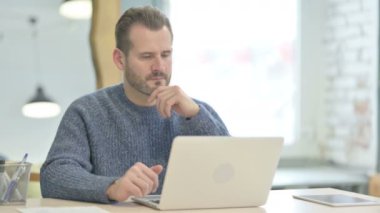 Mature Adult Man Thinking while Working on Laptop