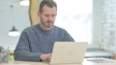Mature Adult Man Leaving Office after Closing Laptop