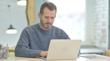 Mature Adult Man Smiling at Camera while using Laptop