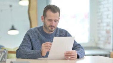 Mature Adult Man Reading Documents in Office, Paperwork
