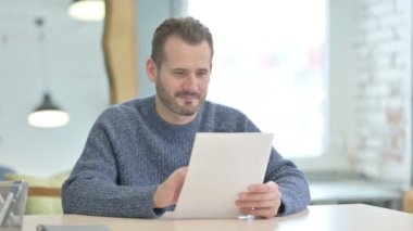 Mature Adult Man Celebrating Success while Reading Documents in Office