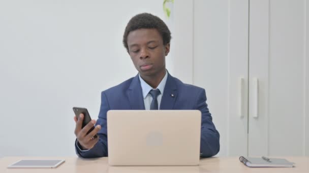 Νεαρός Αφρικανός Επιχειρηματίας Που Χρησιμοποιεί Smartphone Και Laptop — Αρχείο Βίντεο