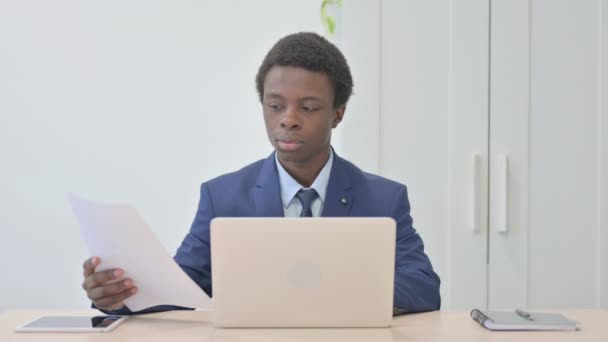 Joven Empresario Africano Celebrando Éxito Línea Mientras Hace Papeleo — Vídeos de Stock