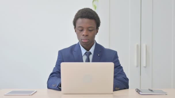 Joven Empresario Africano Mirando Cámara Mientras Usa Ordenador Portátil — Vídeos de Stock