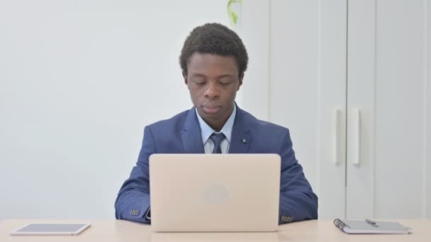 年轻的非洲商人一边用笔记本电脑一边在相机前微笑 — 图库视频影像