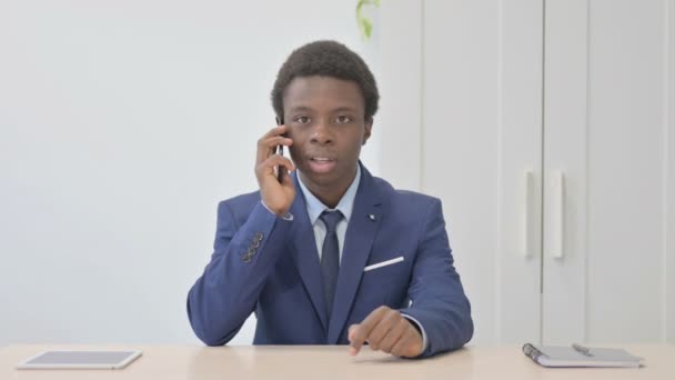 若いアフリカのビジネスマンがオフィスで電話で話している — ストック動画