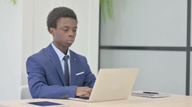 African Businessman Shaking Head in Rejection while Working on Laptop