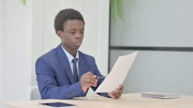 African Businessman Reading Documents in Office, Paperwork