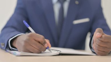 Close up of African Businessman Writing in Office