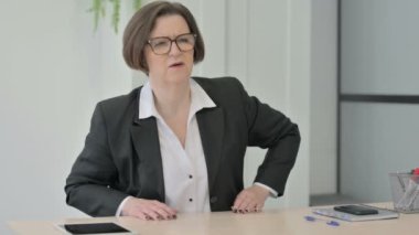 Yaşlı kıdemli iş kadını dizüstü bilgisayar kullanırken sırt ağrısı çekiyor