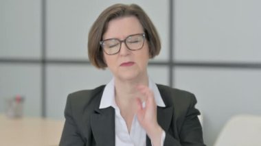 Yorgun yaşlı iş kadını boynuna masaj yapıyor, vücudunu geriyor.
