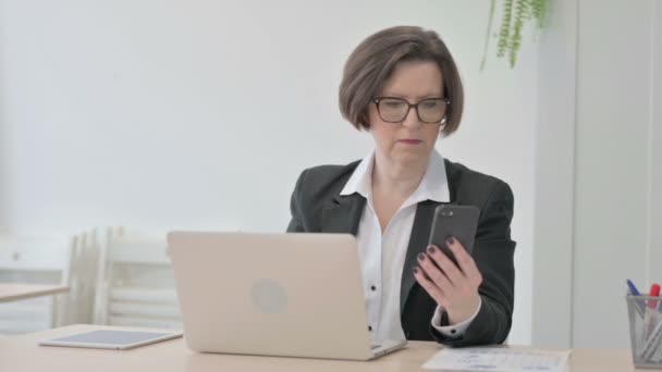 Old Senior Businesswoman Using Smartphone While Using Laptop — Vídeo de stock