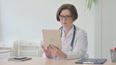 Old Senior Doctor Browsing Tablet in Clinic