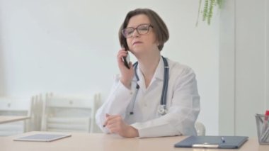 Old Senior Doctor Talking on Phone in Clinic