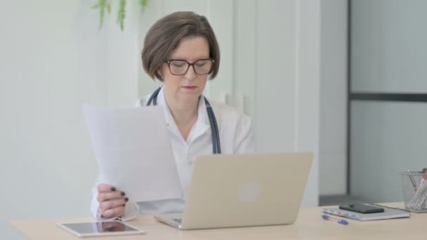Doctora Senior Trabajando Documentos Laptop Clínica — Vídeos de Stock