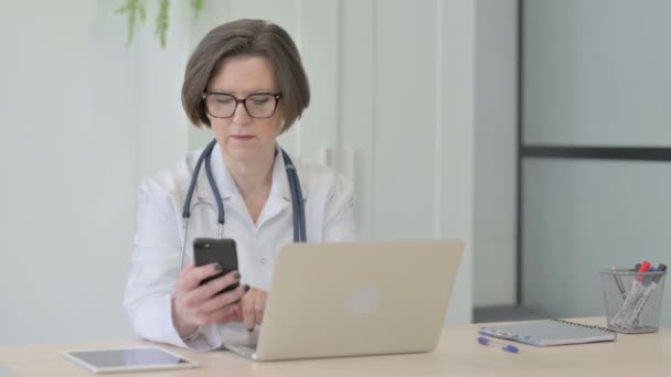 Doutor Senior Feminino Falando Telefone Enquanto Estiver Usando Laptop — Vídeo de Stock