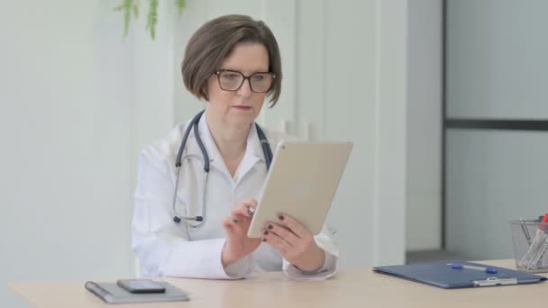 Médica Sênior Navegando Tablet Clínica — Vídeo de Stock