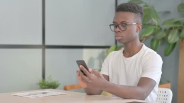 Young African Man Browsing Internet on Smartphone in Office