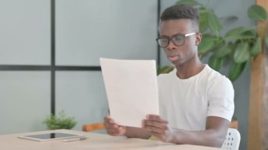 Young African Man Reading Documents in Office, Paperwork
