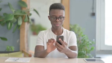 African Man Celebrating Win on Smartphone