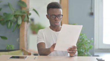 African Man Reading Documents in Office, Paperwork