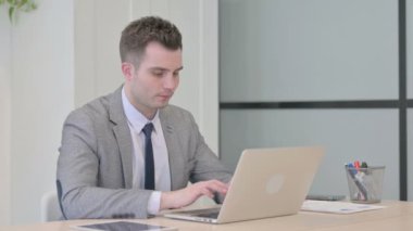 Genç İşadamı Bilgisayarı kullanırken Kameraya Bakıyor