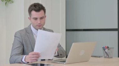 Dizüstü bilgisayar ve Belgeler üzerinde çalışırken Başarı Kutlaması Genç İşadamı