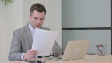 Young Businessman Upset by Loss while Working on Laptop and Documents