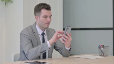 Successful Young Businessman Celebrating Win on Smartphone