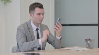 Öfkeli Genç İş Adamı İş yerinde Akıllı Telefonla Konuşuyor