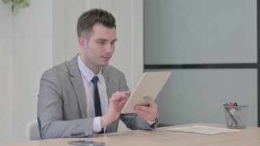 Young Businessman Celebrating Win on Digital Tablet