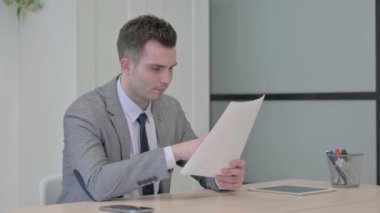 Young Businessman Celebrating Success while Reading Documents