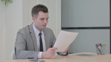 Young Businessman Reading Documents in Office, Paperwork