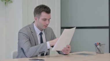 Young Businessman Upset by Loss while Reading Business Report