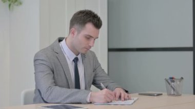 Young Businessman Working on Documents and Calculating Business Data