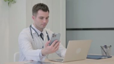 Young Doctor using Smartphone while using Laptop