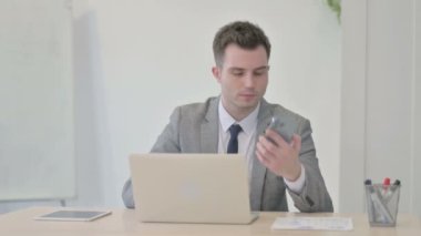 Genç işadamı dizüstü bilgisayar kullanırken telefonda konuşurken