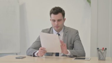 Young Businessman Reading Documents in Office, Paperwork