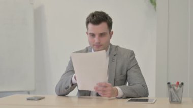 Young Businessman Celebrating Success while Reading Documents