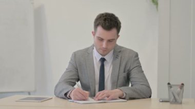 Young Businessman Working on Documents and Calculating Business Data