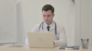 Young Doctor Looking at Camera while using Laptop